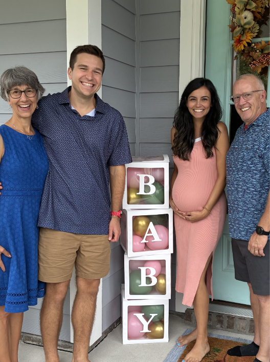 A group picture in front of balloons that spell 'baby'